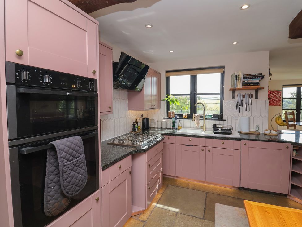 A kitchen with pink cabinets and stove at Hedgerose in Goodleigh near Barnstaple