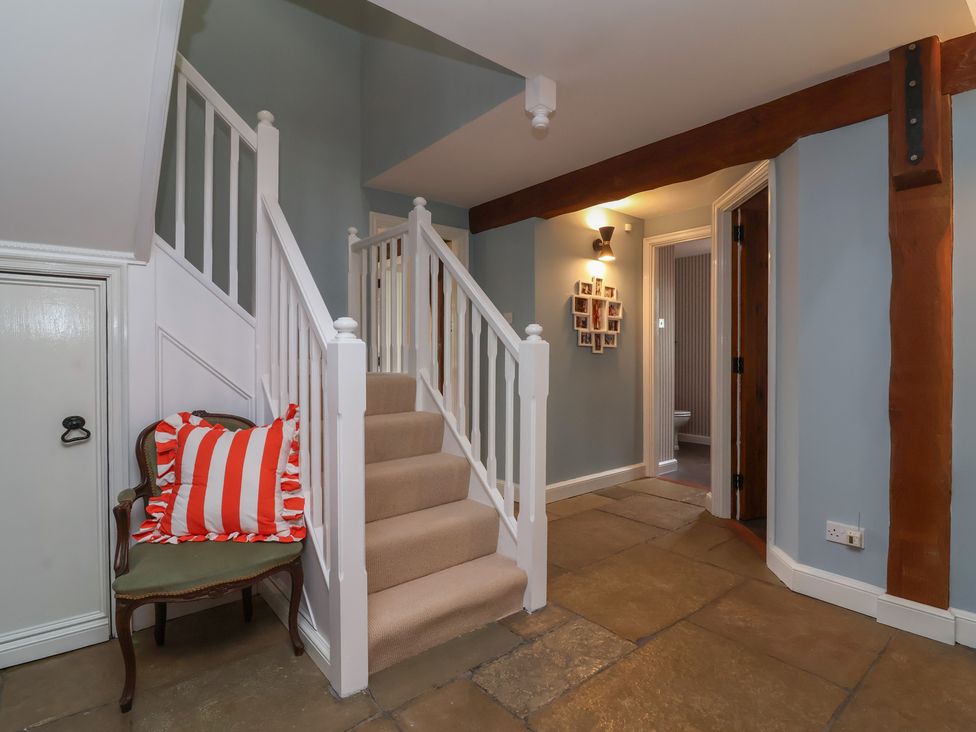 A hallway with a staircase and chair at Hedgerose Goodleigh near Barnstaple