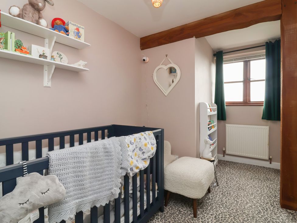 A nursery with a crib and shelves at Hedgerose Goodleigh near Barnstaple
