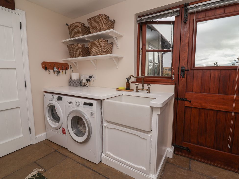 A laundry room with a washer and dryer and a utility sink at Hedgerose in Goodleigh near Barnstaple