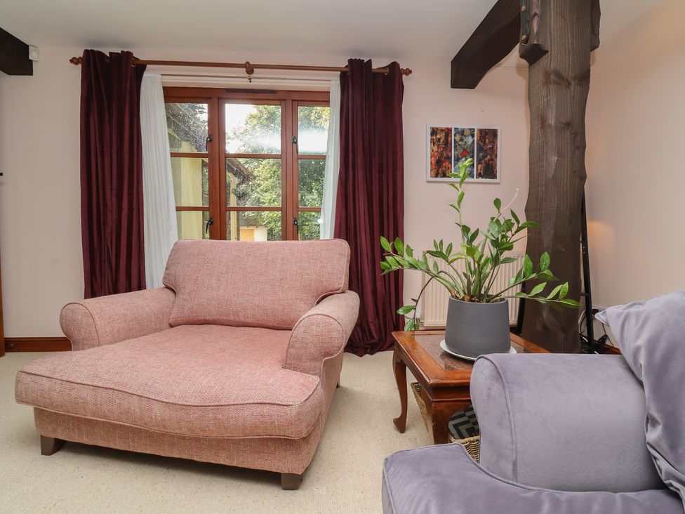 A living room with a pink sofa and a potted plant at Hedgerose in Goodleigh near Barnstaple