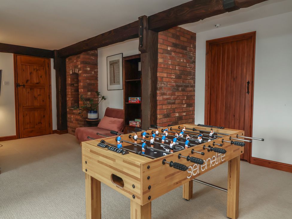 A foosball table with a brick wall and wooden door in a snug at Hedgerose Goodleigh near Barnstaple
