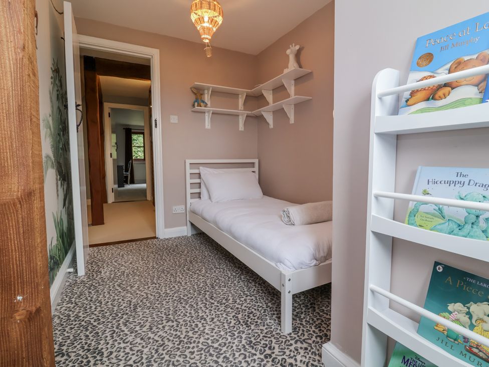 A bedroom with a single bed and books on a shelf at Hedgerose in Goodleigh near Barnstaple