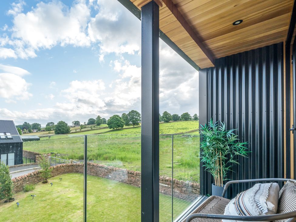 A balcony with chairs and a potted plant overlooking a field at 