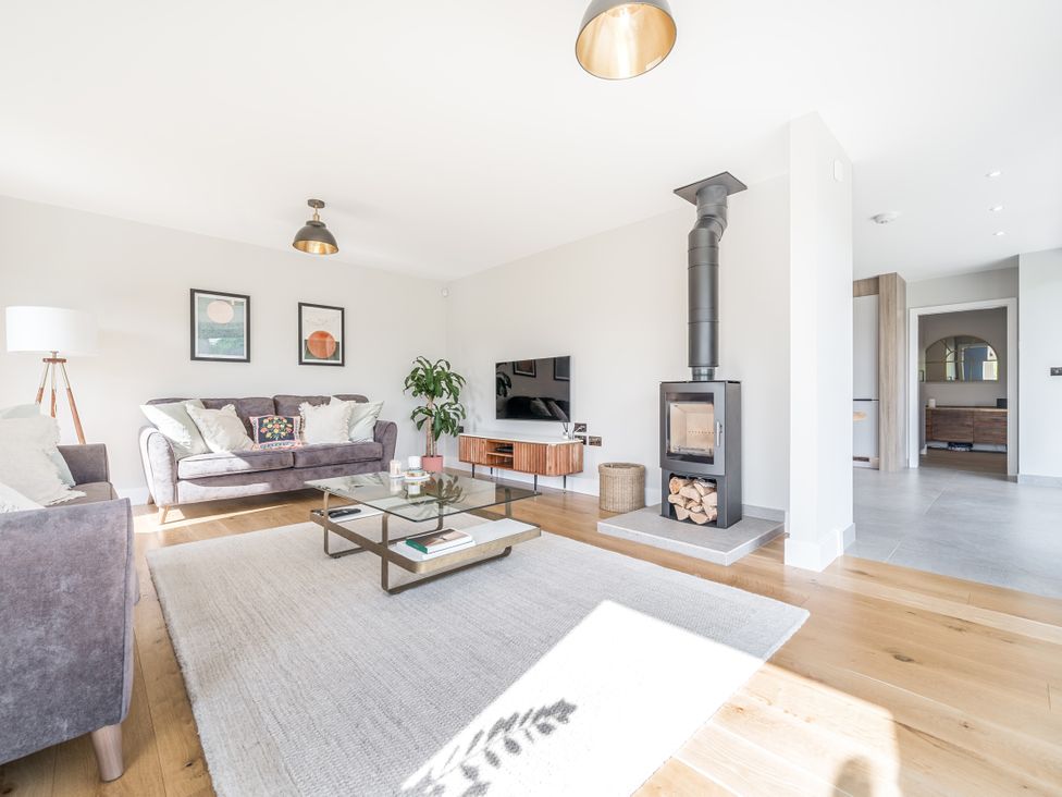 A living room with a sofa, coffee table, and wood stove at The Old Barn in Manchester