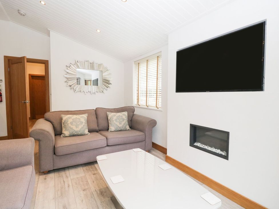 A living room with a sofa and television at Easedale Lodge, Waterside Wood 2, White Cross Bay near Windermere