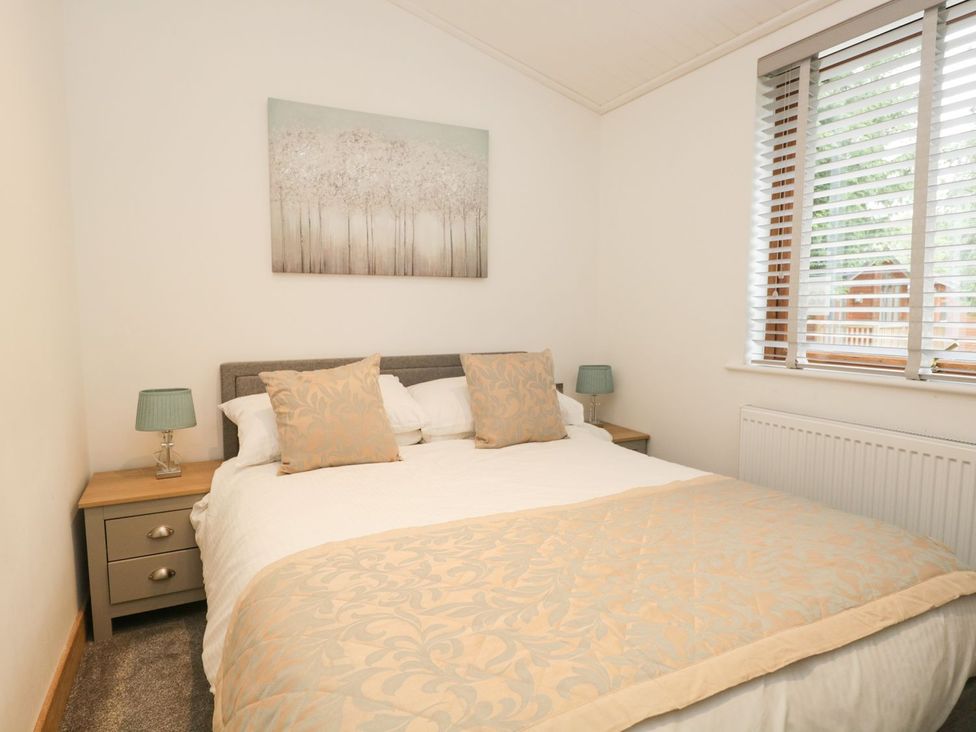 A bedroom with a bed and bedside table at Easedale Lodge, Waterside Wood 2, White Cross Bay near Windermere