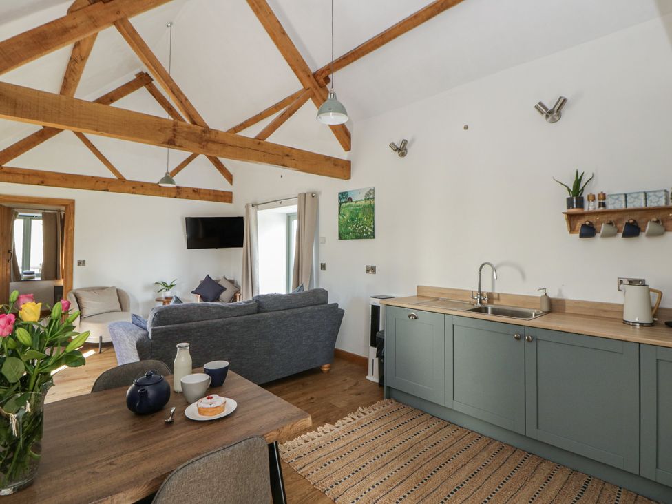 A living room with a sofa and kitchen area at Eleri’s Barn Nantmel near Rhayader