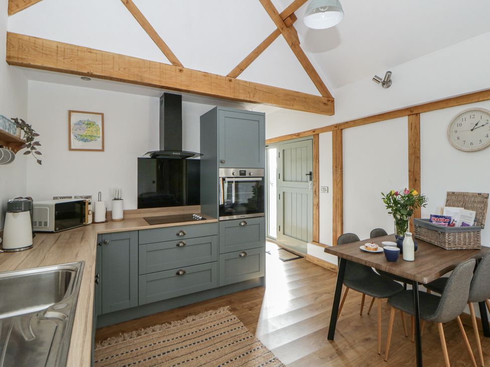 A kitchen with cabinets and a dining table at Eleri’s Barn Nantmel near Rhayader