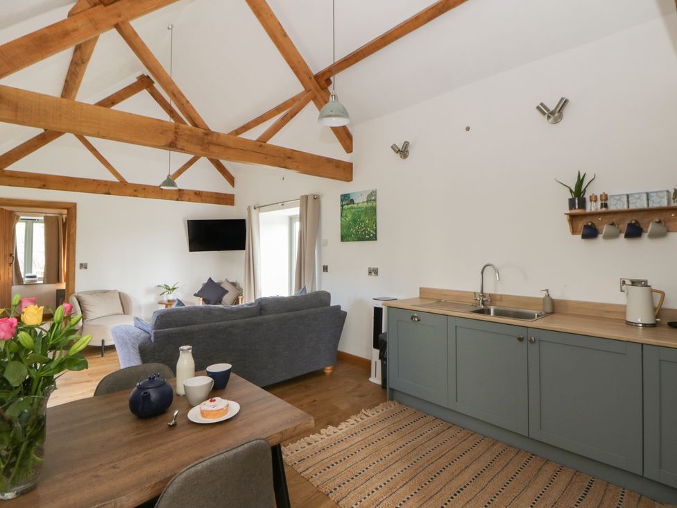 A living room with a dining area and kitchen sink at Eleri’s Barn Nantmel near Rhayader