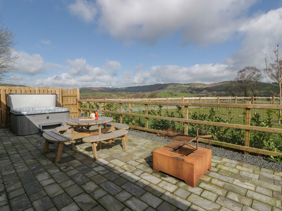 An outdoor area with a hot tub, picnic table, and fire pit at Eleri’s Barn Nantmel near Rhayader