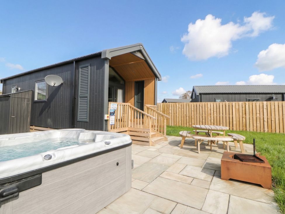 A hot tub and seating area outside a lodge at Daverneithon 1 near Llandrindod Wells