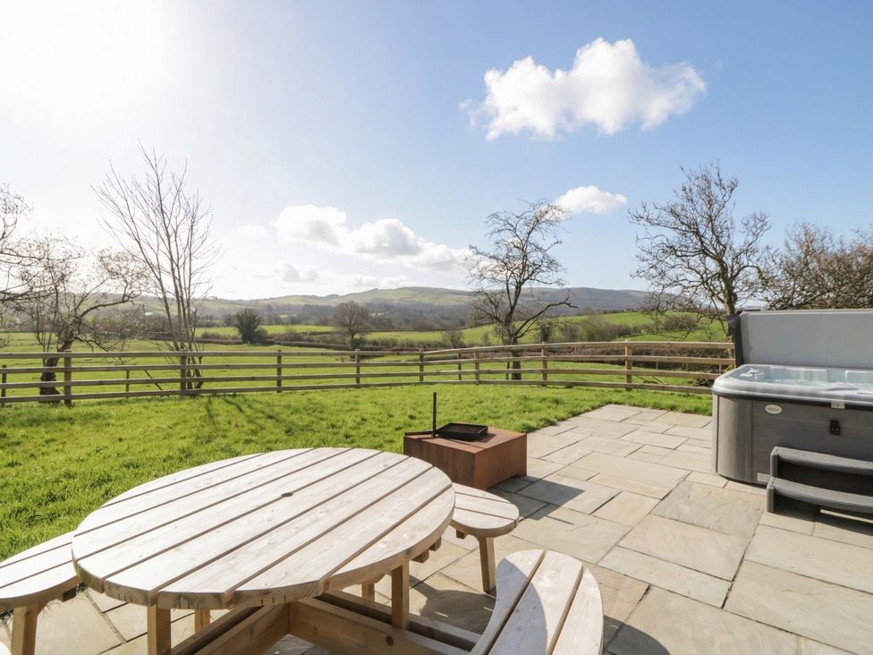 An outdoor area with a table and chairs, hot tub and views at Daverneithon 1 Near Llandrindod Wells