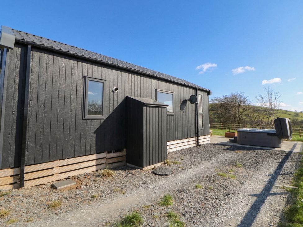 An outdoor area with a cabin, hot tub and gravel pathway at Daverneithon 1 near Llandrindod Wells