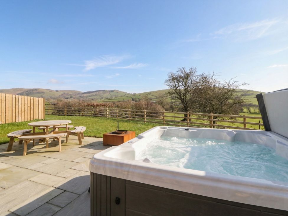 An outdoor area with a hot tub and picnic table at Daverneithon 2 near Llandrindod Wells