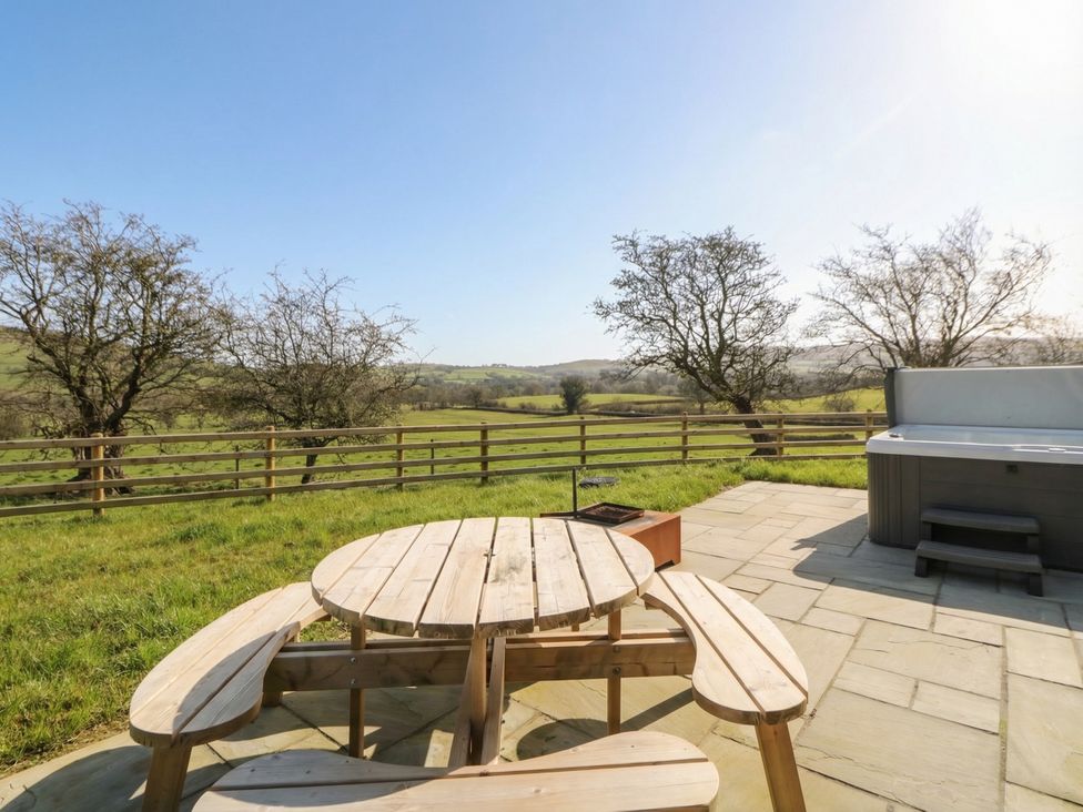An outdoor area with a table and hot tub at Daverneithon 2 near Llandrindod Wells