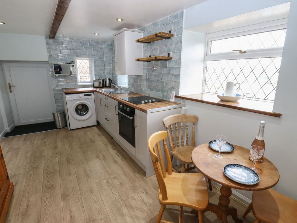 A kitchen with washing machine and dining table at 11 Hollin Well Cottage Sowerby Bridge