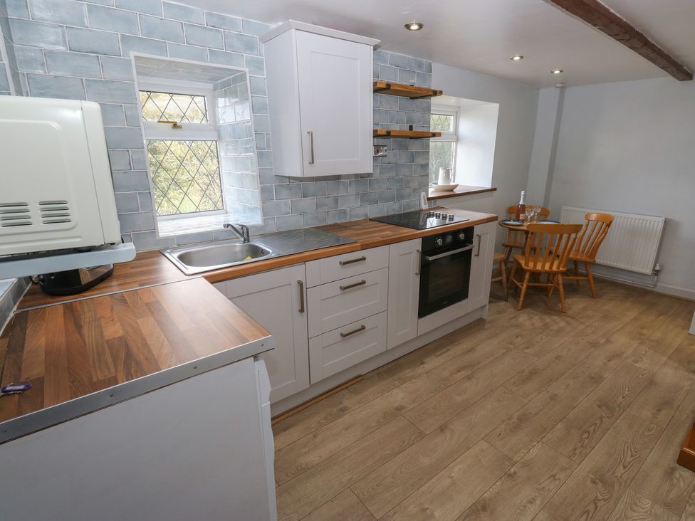 A kitchen with cabinets and a table at 11 Hollin Well Cottage in Sowerby Bridge
