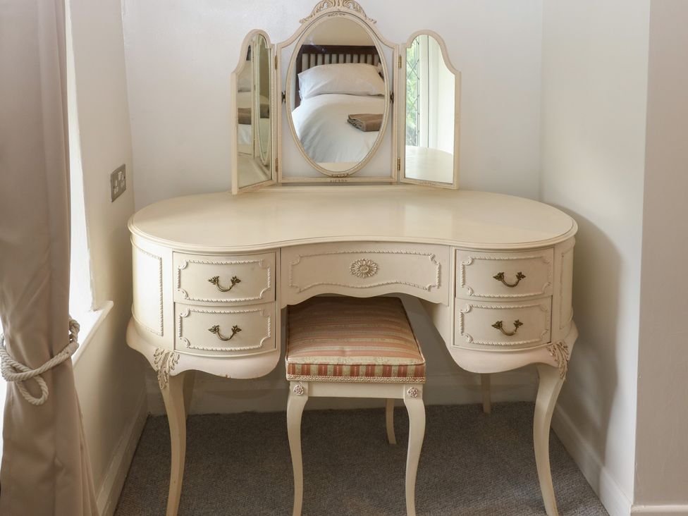 A vanity desk with a mirror and a chair at 11 Hollin Well Cottage in Sowerby Bridge