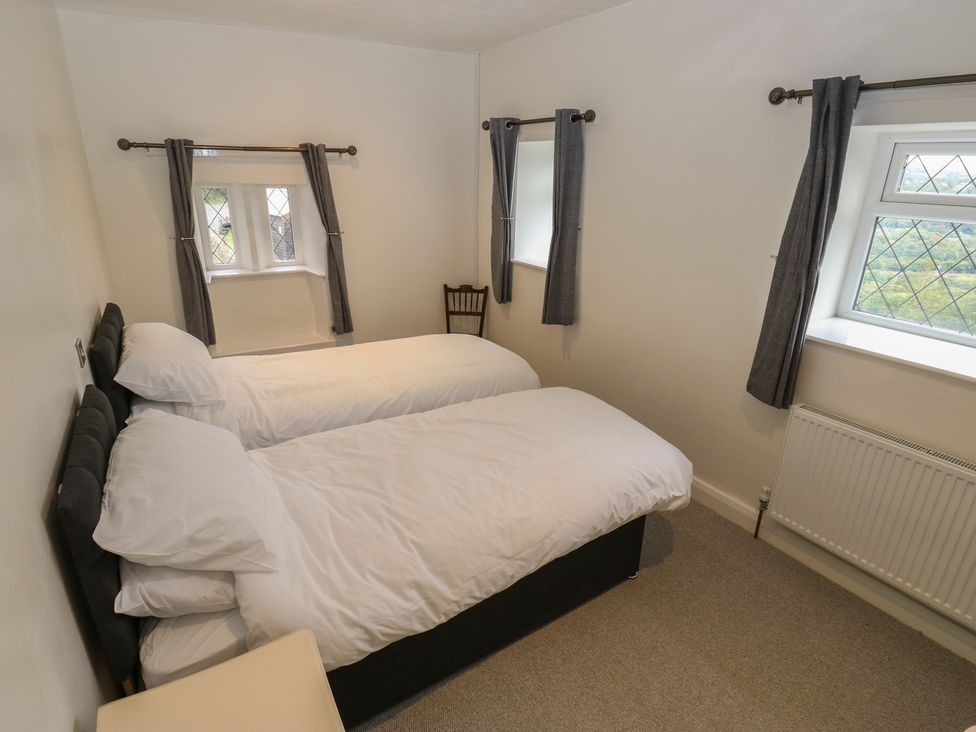 A bedroom with two beds and a chair at 11 Hollin Well Cottage in Sowerby Bridge