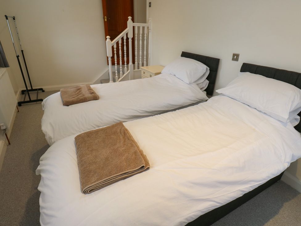 A bedroom with twin beds and towels at 11 Hollin Well Cottage in Sowerby Bridge