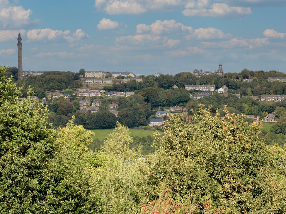 A landscape view of houses and greenery with a monument at 11 Hollin Well Cottage in Sowerby Bridge