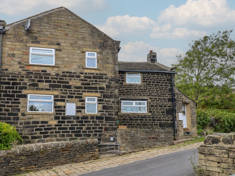 A stone building with windows and a pathway at 11 Hollin Well Cottage Sowerby Bridge