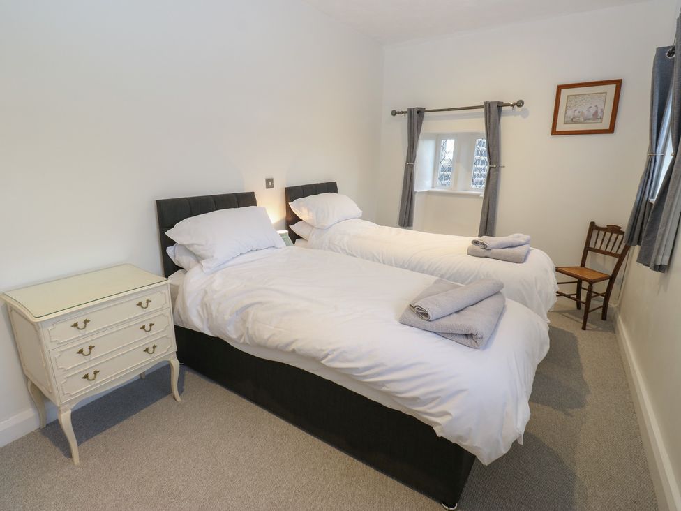 A bedroom with two single beds and a chair at 11 Hollin Well Cottage in Sowerby Bridge