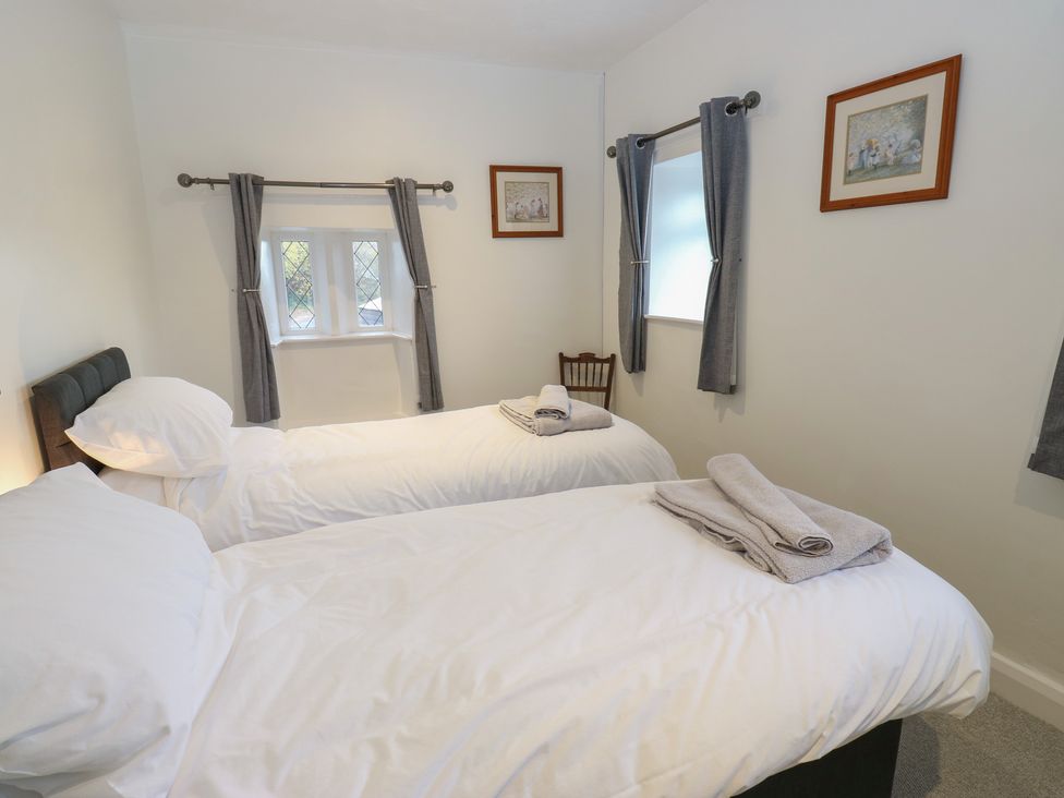 A bedroom with two beds and a window at 11 Hollin Well Cottage Sowerby Bridge