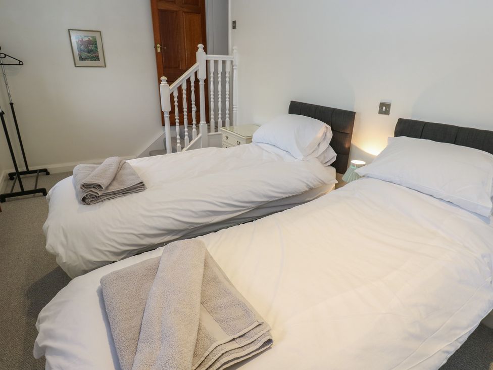 A bedroom with two single beds and a clothing rack at 11 Hollin Well Cottage Sowerby Bridge