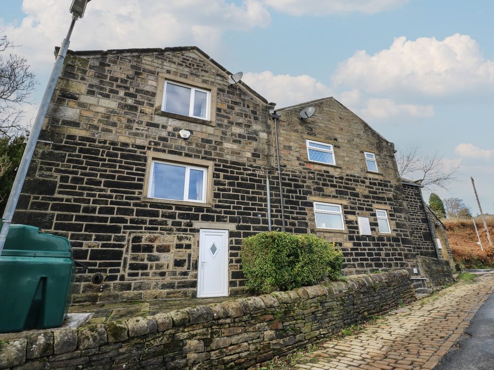 An exterior view of a stone building with windows and a door at 11 Hollin Well Cottage Sowerby Bridge