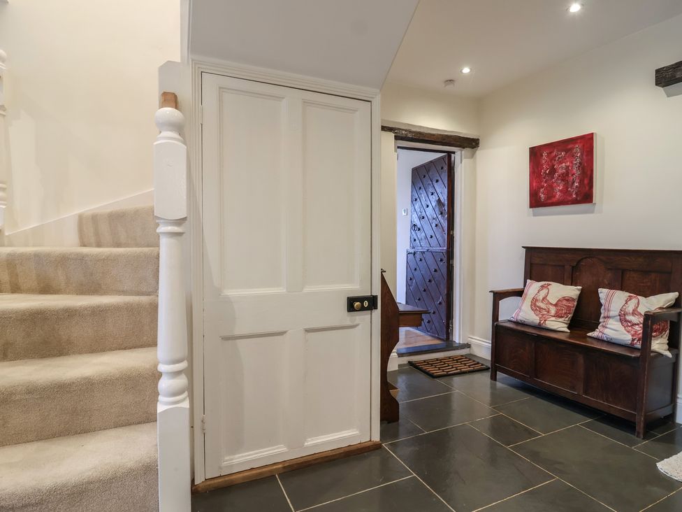 A hallway with a bench and staircase at The Old Manor House in Lifton
