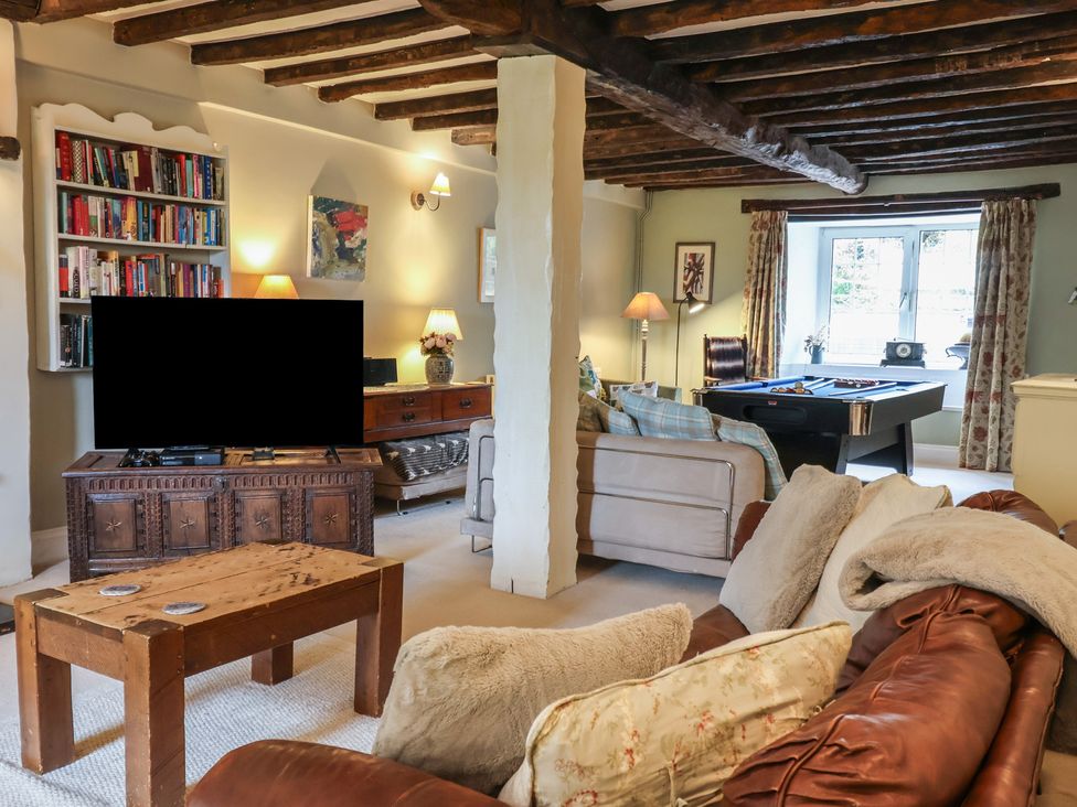 A living room with a sofa, television, bookshelf, and pool table at The Old Manor House in Lifton