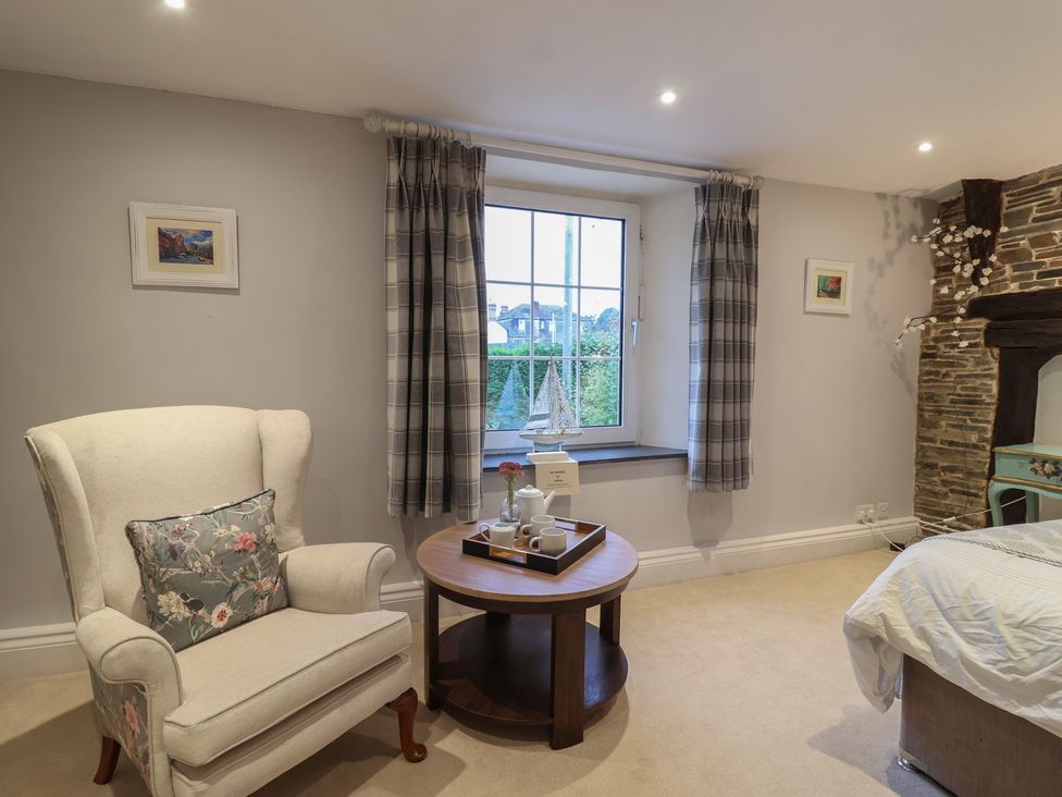 A bedroom with an armchair and side table at The Old Manor House in Lifton