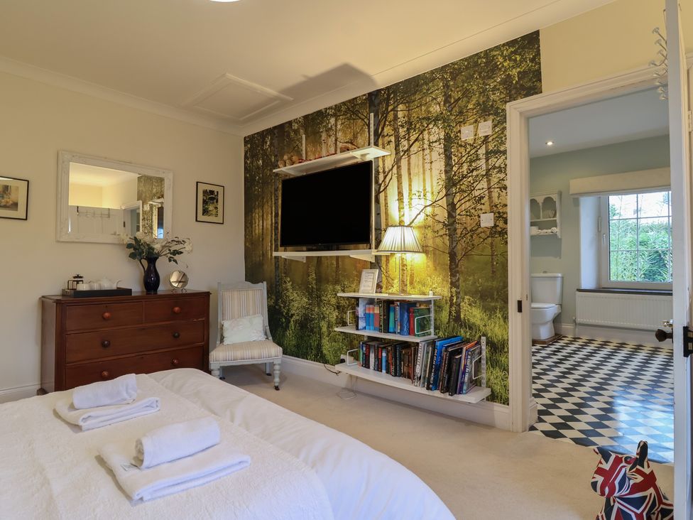 A bedroom with a television and bathroom access at The Old Manor House in Lifton
