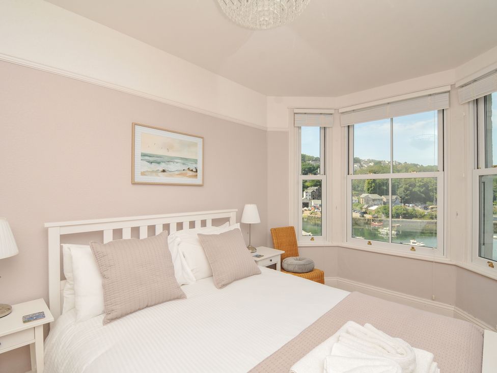 A bedroom with a bed and windows overlooking a view at Overdale in Looe