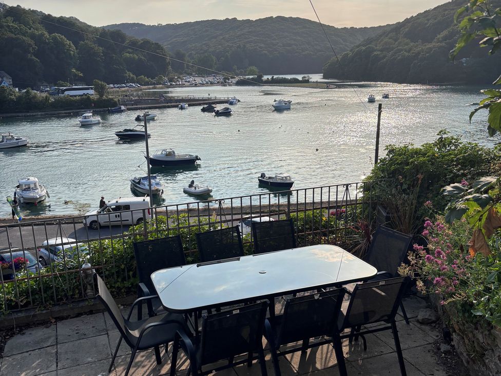 A table and chairs overlooking water with boats at Overdale in Looe