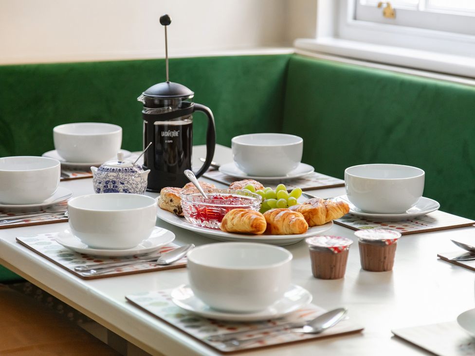 A dining table set with coffee, cups, croissants, and grapes at Castle View in Windsor, Berkshire