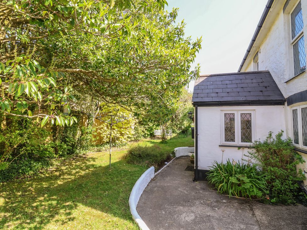 A garden with a pathway and trees at Honey Cottage in Ilfracombe