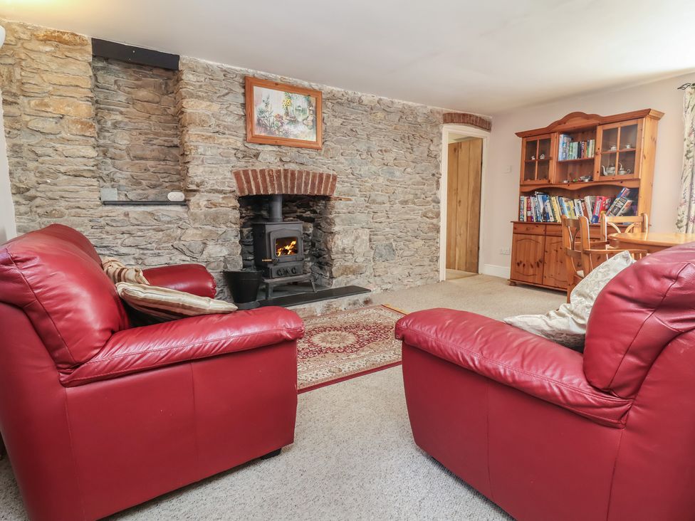 A living room with a fireplace and sofa at Honey Cottage, Ilfracombe