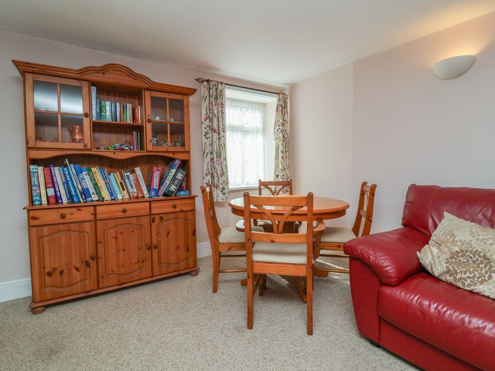 A dining room with a table, chairs, and a bookshelf at Honey Cottage Ilfracombe