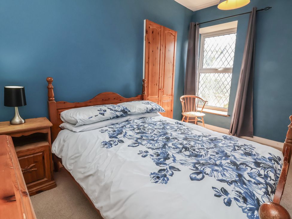 A bedroom with a bed and nightstand at Honey Cottage in Ilfracombe
