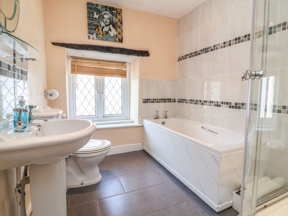 A bathroom with a sink, toilet, bathtub, and shower enclosure at Honey Cottage in Ilfracombe