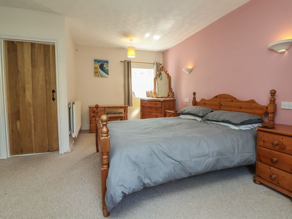 A bedroom with a bed and dressing table at Honey Cottage Ilfracombe