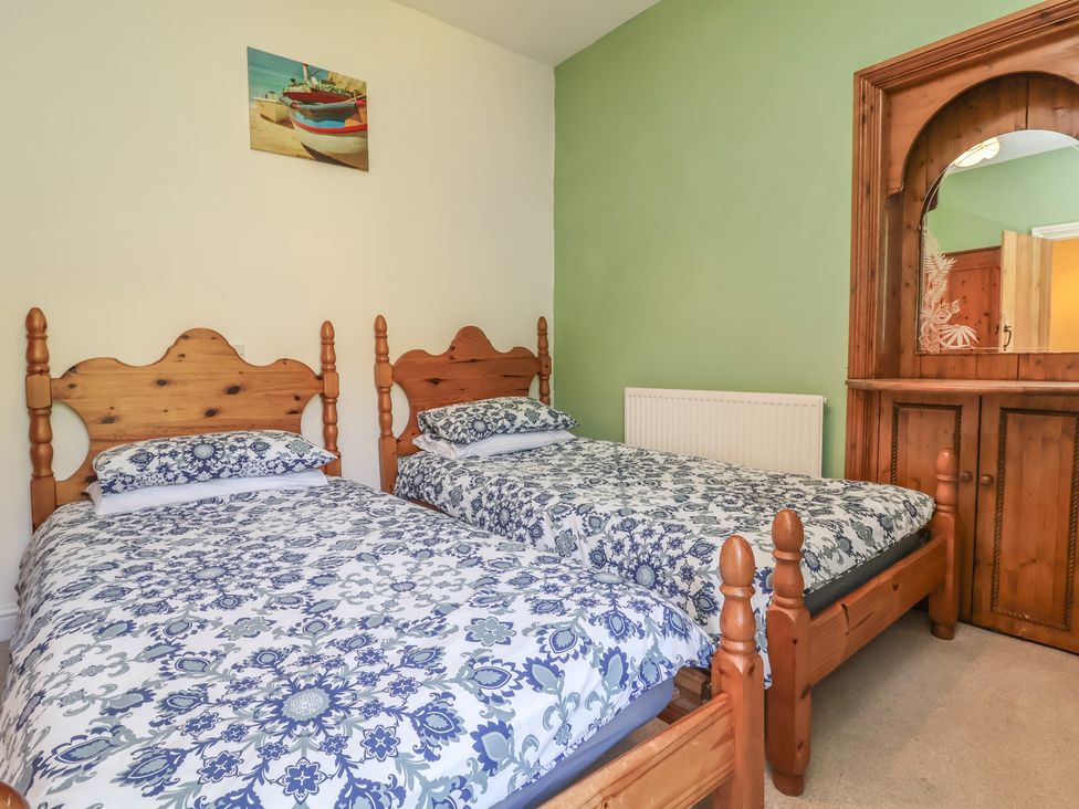 A bedroom with two beds and a wooden dresser at Honey Cottage in Ilfracombe