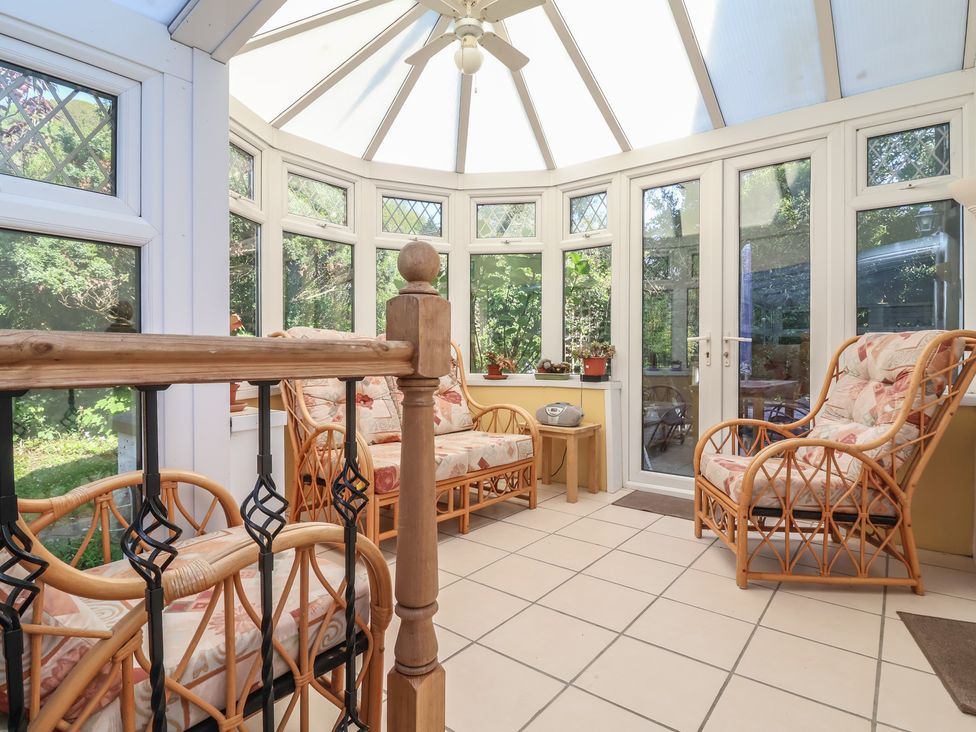 A conservatory with rattan chairs and a table at Honey Cottage in Ilfracombe