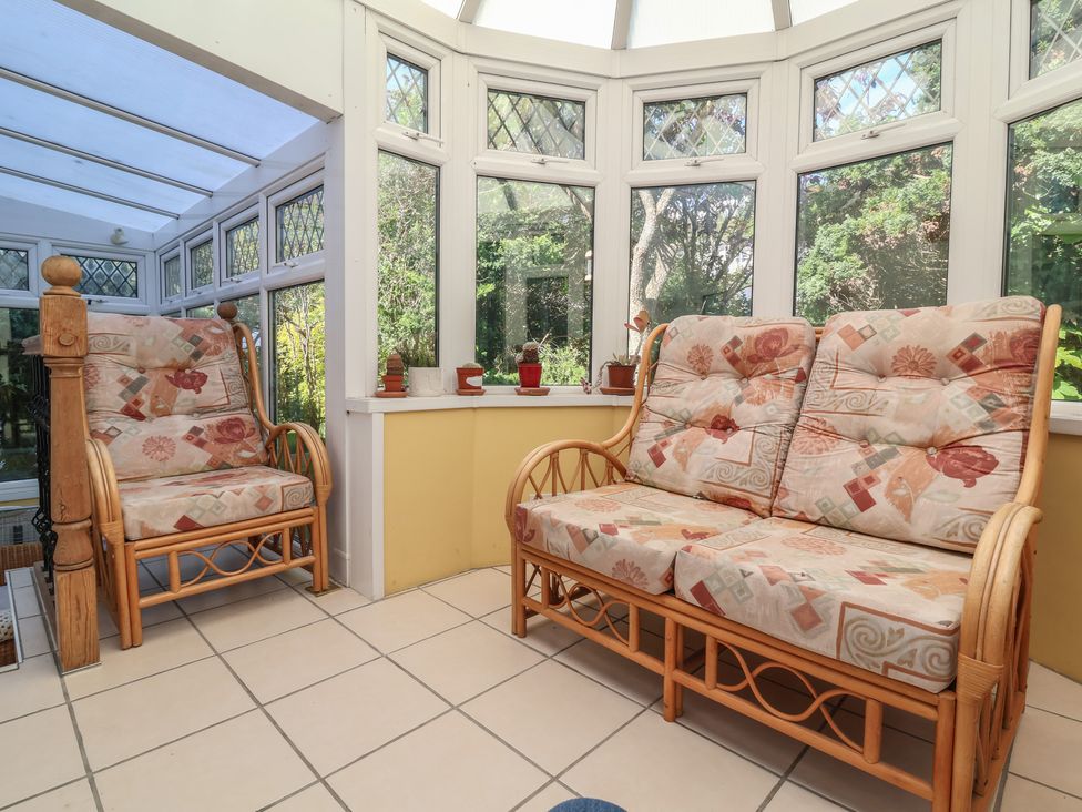 A conservatory with rattan chair and sofa at Honey Cottage in Ilfracombe