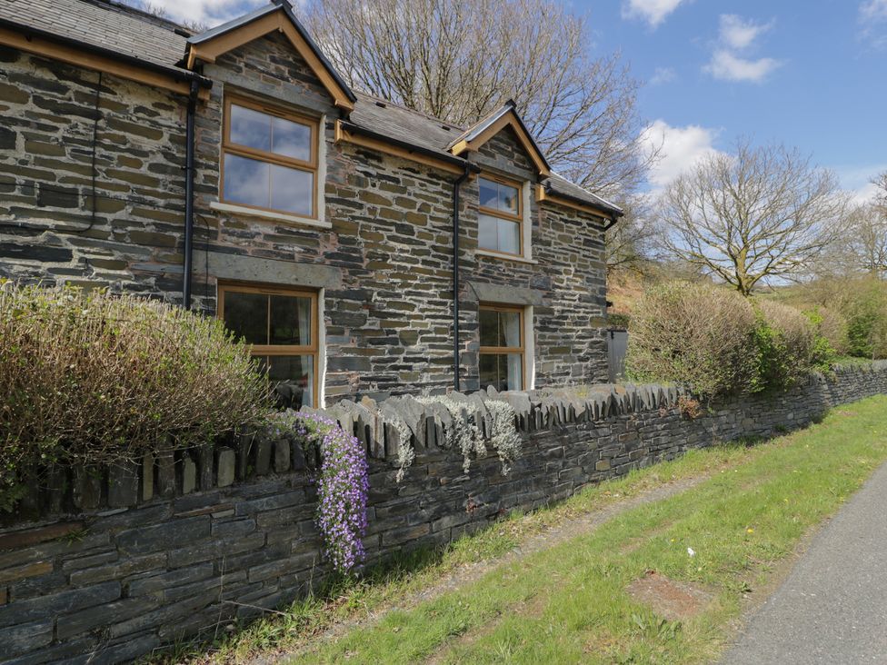 An outdoor view of a stone building with windows and a pathway at Ysgoldy in Dolwyddelan