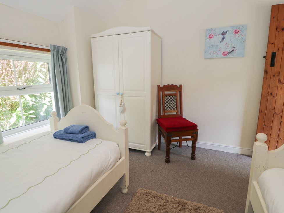 A bedroom with a bed, towel, wardrobe, chair and window at Ysgoldy in Dolwyddelan