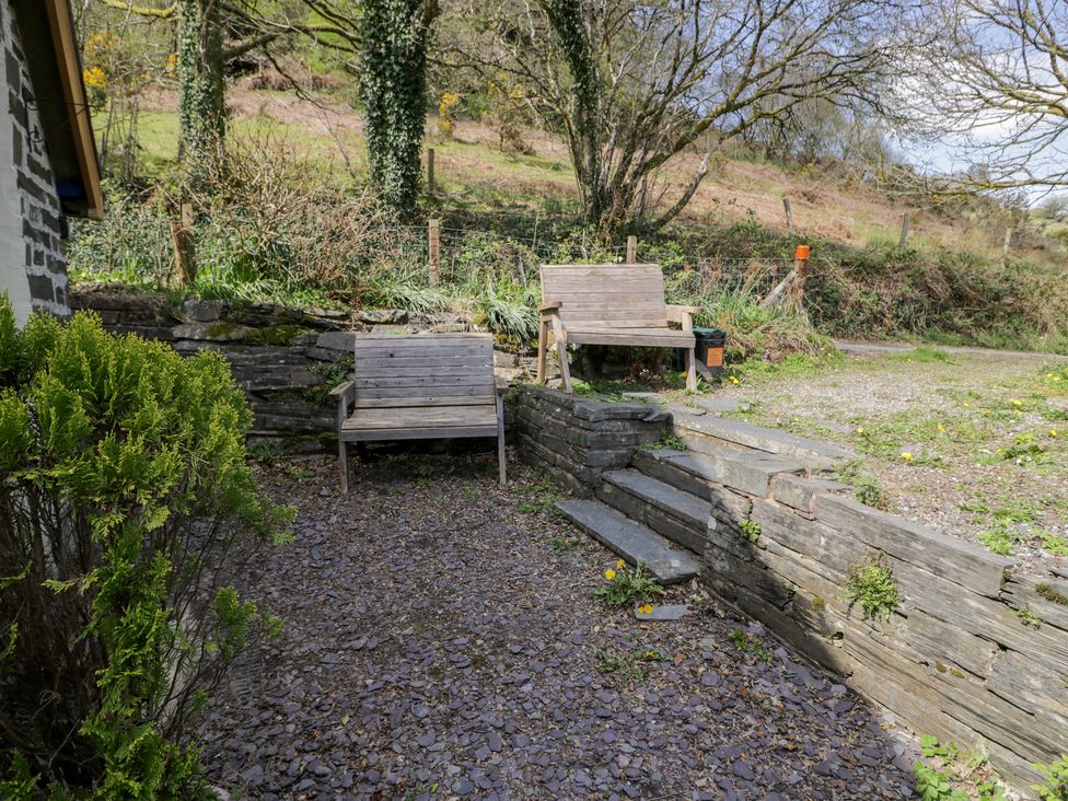 A garden with wooden benches and stone steps at Ysgoldy in Dolwyddelan